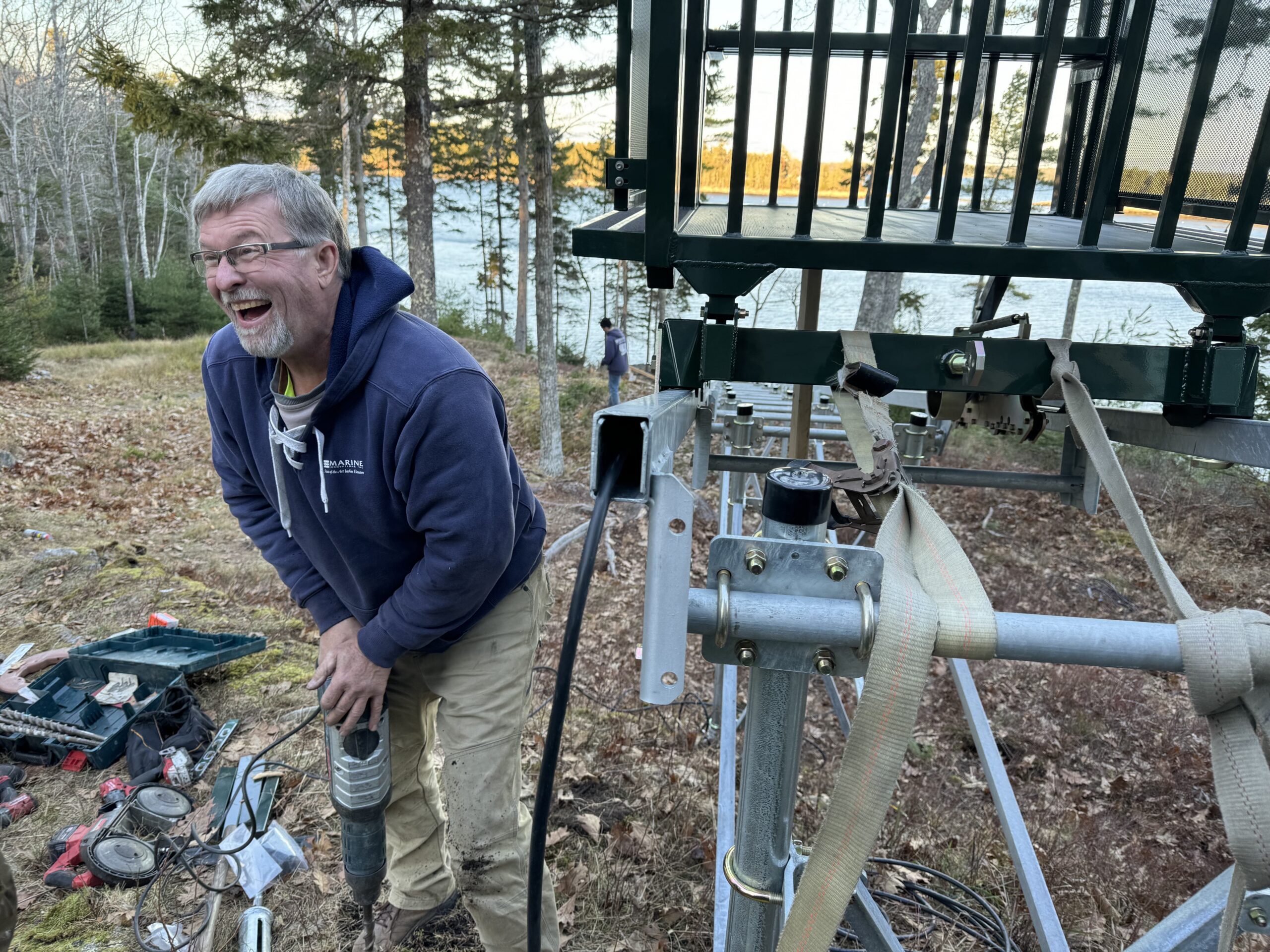 Man drilling beside outdoor metal platform