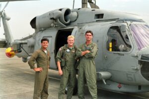 Three aircrew in flight suits by helicopter
